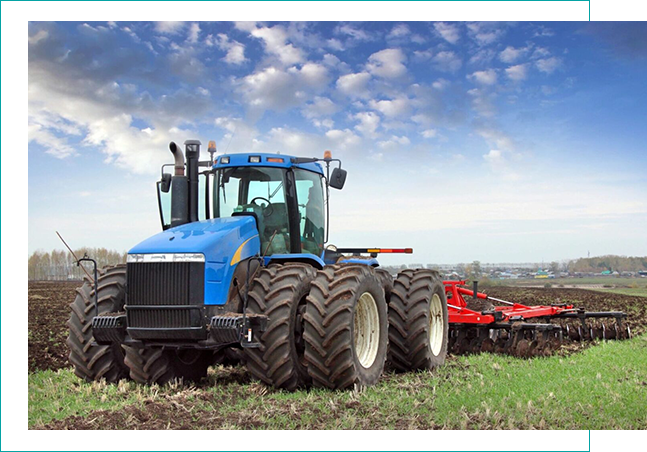 Blue tractor plowing field under cloudy sky. Blue tractor plowing field under cloudy sky.