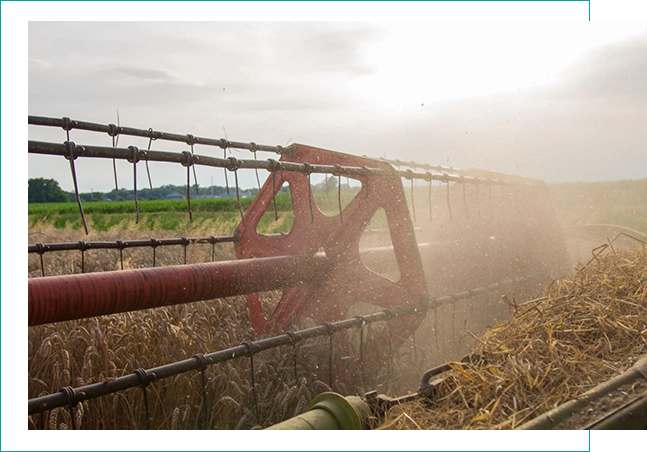 Red tractor plowing field under cloudy sky.